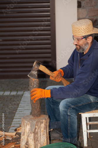 Man with glasses chopping wood in courtyard of house
