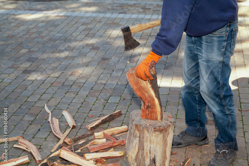 Man in jeans chopping wood in yard