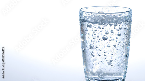 Clean minimalist product photography of a glass of refreshing ice-cold sparkling water with condensation droplets on a bright isolated white background for hydration advertising.