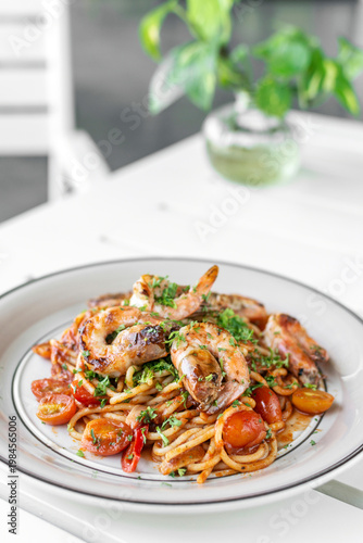 shrimp and tomato diavolo spicy spaghetti on white table at outdoor restaurant in italy