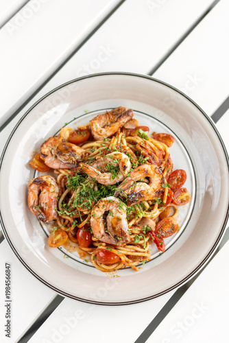 shrimp and tomato diavolo spicy spaghetti on white table at outdoor restaurant in italy