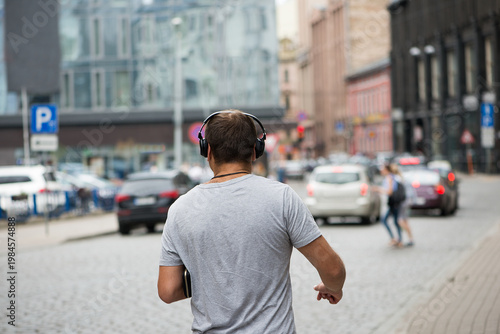 Man Listening To Music While Walking Through City Street