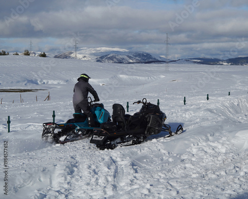 Obraz na plátně Two snowmobiles on snowy mountain terrain with riders enjoying a winter adventure and extreme outdoor sport