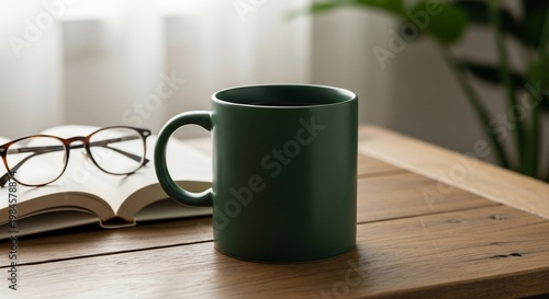 Cozy Still Life: Green Mug, Open Book, and Glasses on Wooden Table