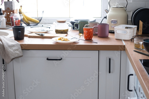 Cluttered kitchen countertop, dirty crockery, leftover food, mess after meal, untidy scene, daily home chaos, dishes everywhere, unorganized cooking area.