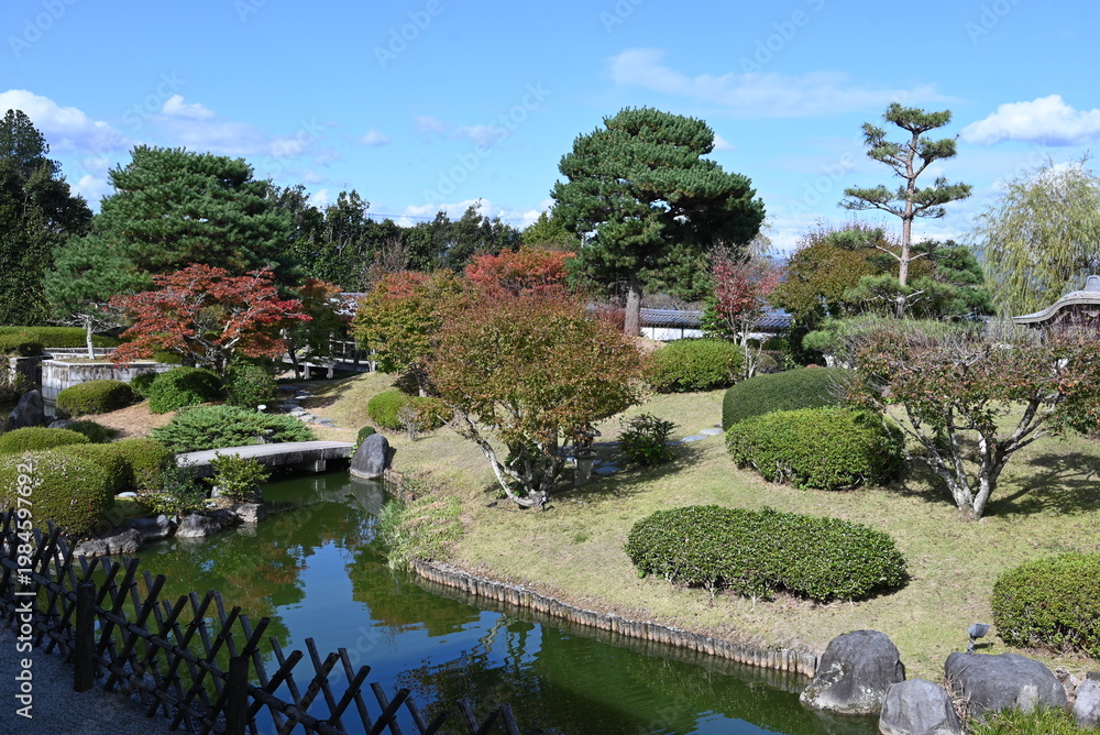 Obraz premium 泉回遊式日本庭園に広がる水辺と緑の美しい風景 Scenic pond-strolling Japanese garden with bridges and manicured greenery