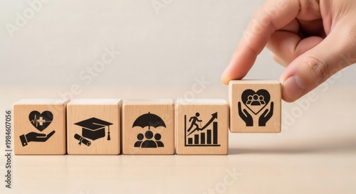 Employee Benefits Concept. Hand placing wooden cube with care icon next to blocks with health education team and growth symbols, representing non cash compensation and employee engagement.
