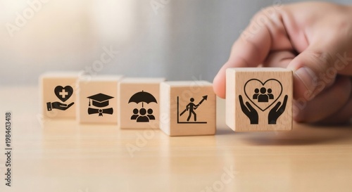 Employee Benefits and Workforce Support Concept. Hand holding wooden cube with care icon in front of benefit related blocks, representing employee retention and attractive compensation strategy.
