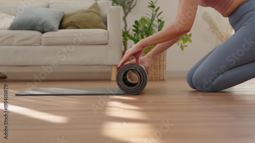 Close up of Asian woman hands rolling up yoga mat on floor