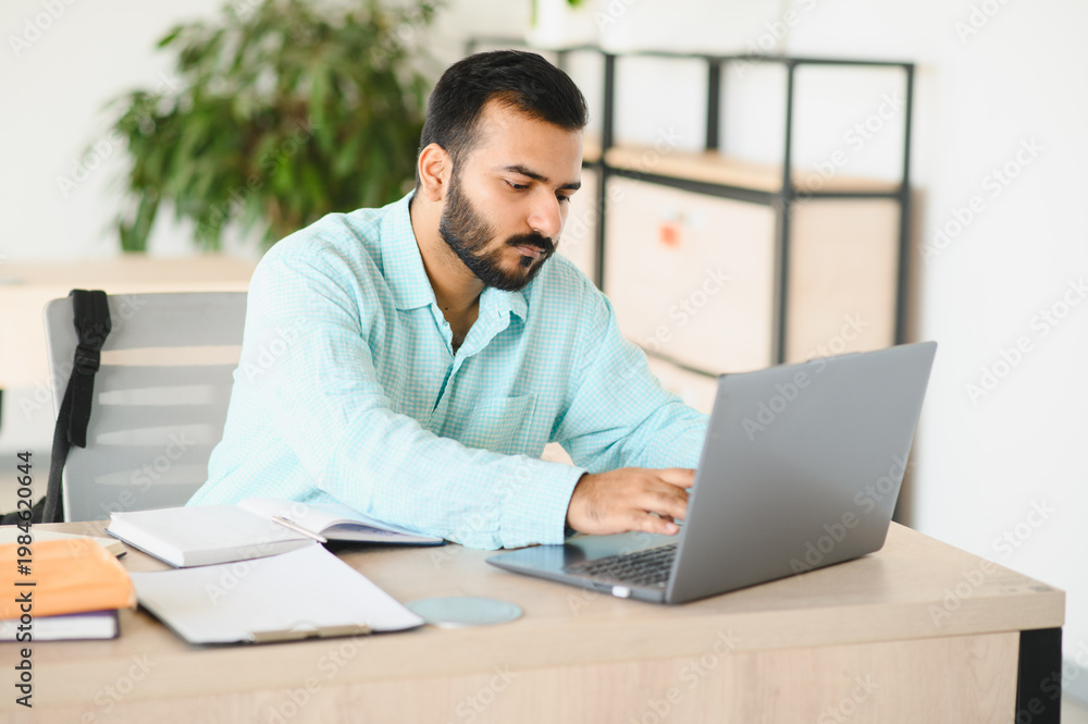 Fototapeta premium Indian student working on laptop, learning in office