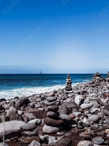 Stone cairns on volcanic beach with ocean waves, Playa del Duque Norte, Tenerife