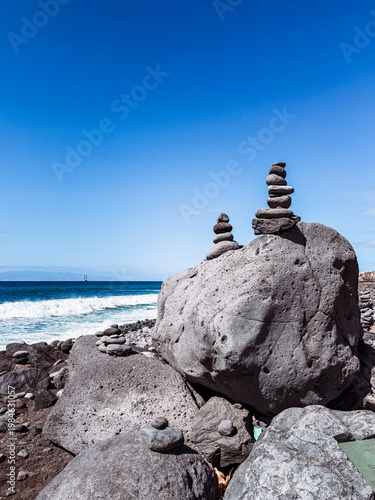 Stone cairns on volcanic beach with ocean waves, Playa del Duque Norte, Tenerife