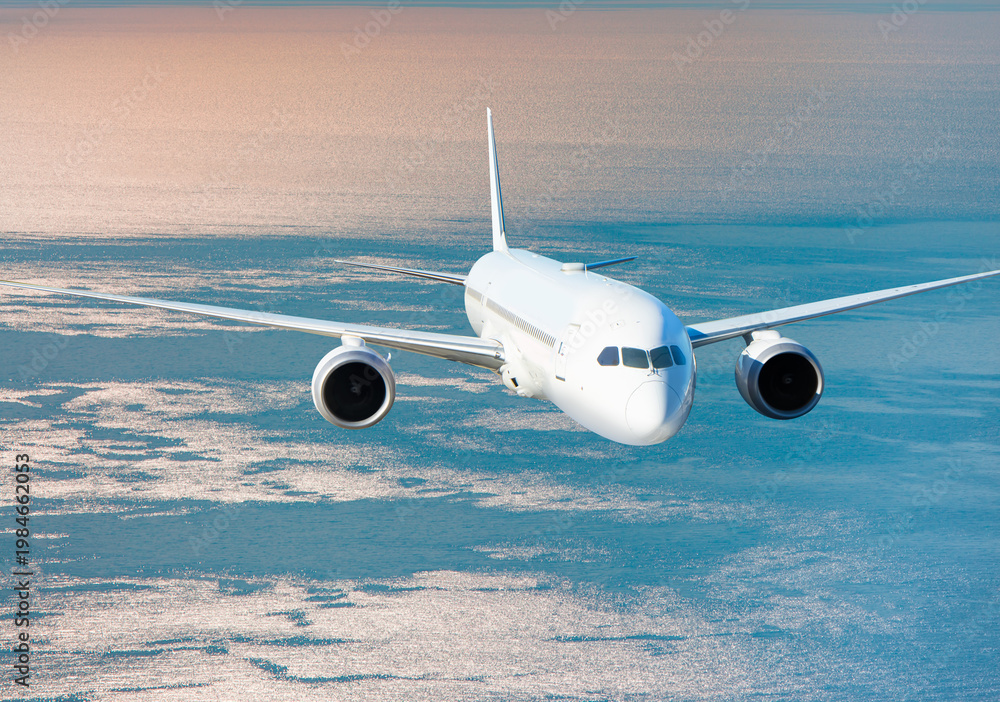 Fototapeta premium Airplane flying over tropical sea at sunset