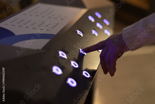 A quiz for visitors to an exhibition or museum, where a finger presses a button to answer or obtain information on a stand.