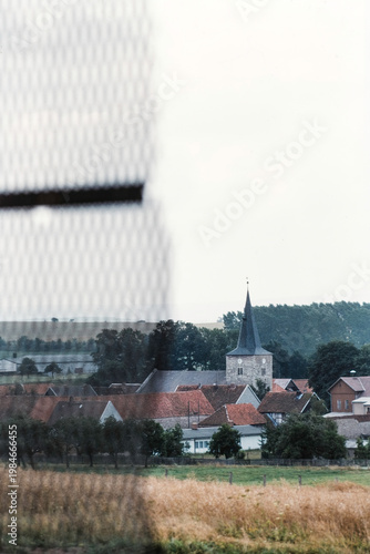 Blick durch einen Grenzzaun von der innerdeutschen Grenze auf eine Gemeinde in Westdeutschland  in der Nähe von Nordhausen, 1990