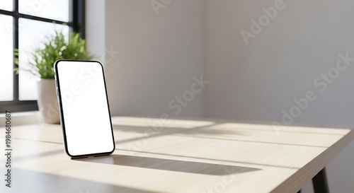 A blank white screen on a modern smartphone placed on a wooden table with natural light