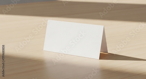 Blank white card placed on a wooden table with soft shadows and light