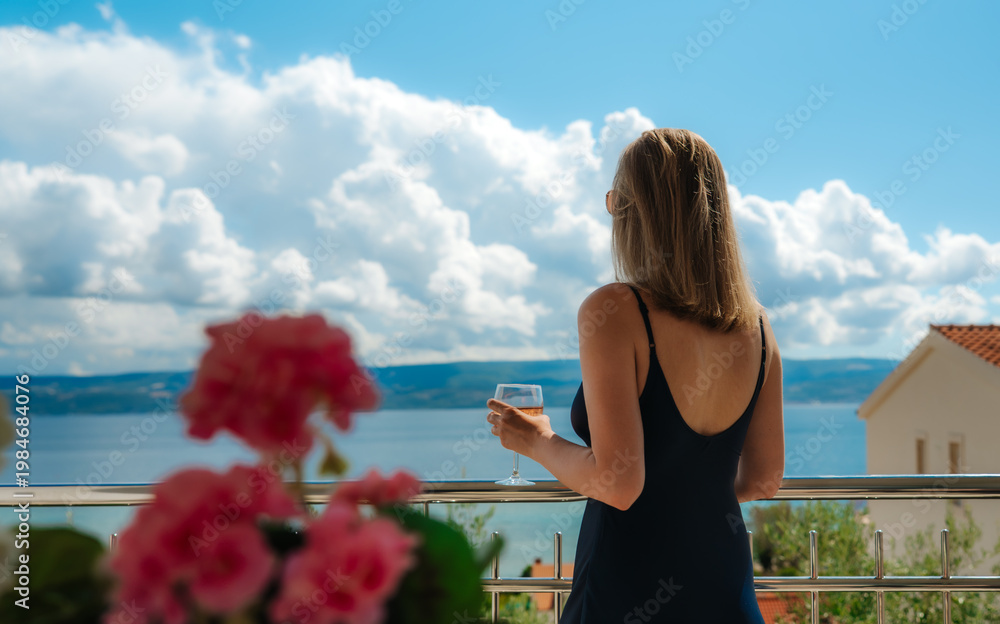 Obraz premium Woman admiring sea view from resort balcony.