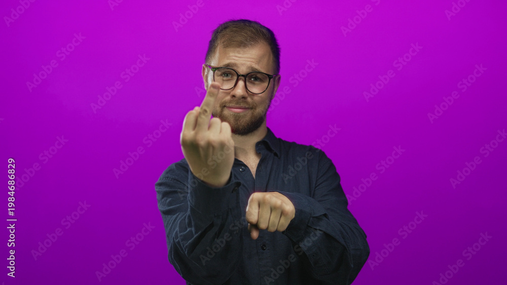 Εκτύπωση καμβά Young man with glasses and beard showing middle finger and clenched fist in magenta studio; defiance attitude