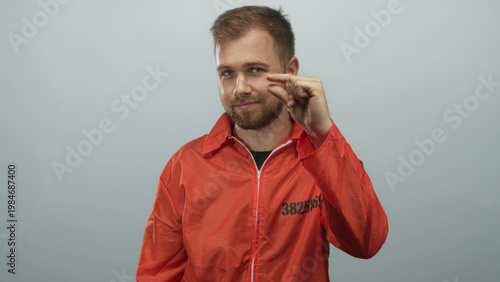 Фотография Man prisoner wearing orange jumpsuit pinches fingers to show small amount in studio with light gray backdrop; confidence defiance