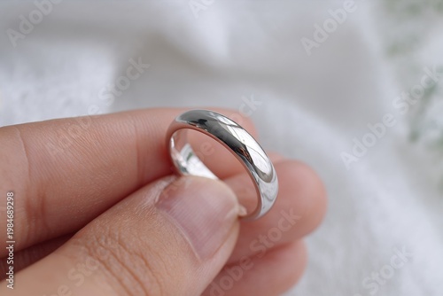 Hand holding silver ring close up on soft background