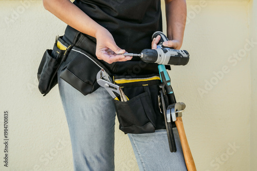Close-up of an anonymous woman doing home renovations with a tool belt and tools