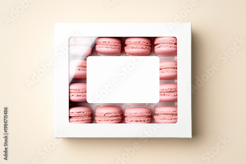 White box with transparent window and blank label filled with pink macarons on soft neutral background