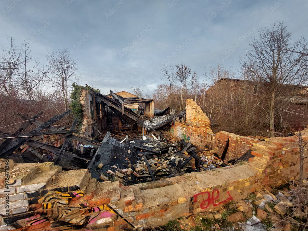 Fototapeta premium Abandoned burned building ruins with brick walls and collapsed structure