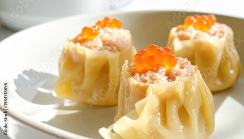 Close-up of savory steamed pork and shrimp shumai dumplings topped with vibrant orange caviar on a white plate