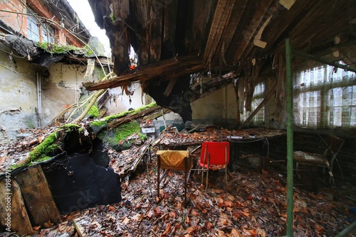Abandoned interior with collapsed roof debris and scattered furniture