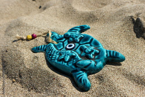 Sea turtle figurine with nazar evil eye, a souvenir on sandy beach