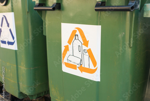 Green recycling bins with recycling symbol showing plastic bottle and containers for sorting waste