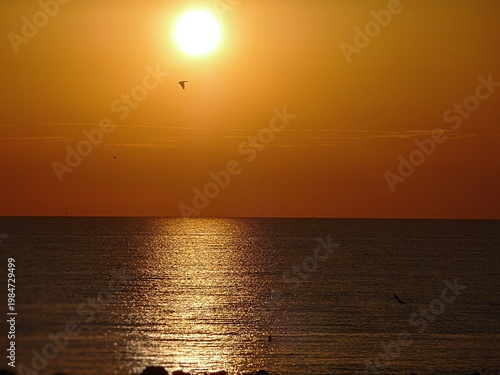 Die Sonne steigt aus dem Meer und färbt den Himmel rot.