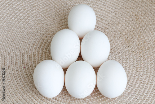 White eggs arranged in pyramid on woven straw background