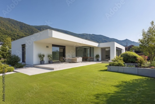 a modern white house with a green lawn and a gray roof