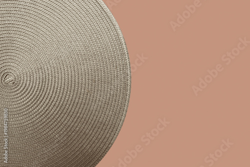 Neutral braided circular placemat on soft blush background with generous copy space