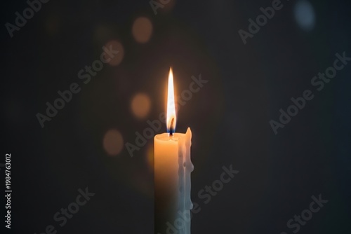 A single lit candle in a dark room with bokeh lights