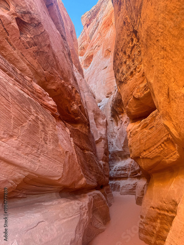 Tall, narrow slot canyon with towering sandstone walls rising steeply on both sides. Valley of Fire State Park, Nevada.