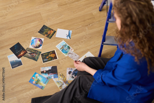 Fényképezés Woman making decisive selection from floor display of photographs