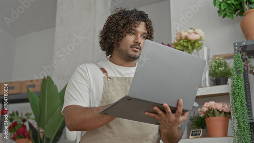 Wallpaper Mural Man florist in apron holds laptop and stylus and points at screen in building; focus inventory planning. Torontodigital.ca