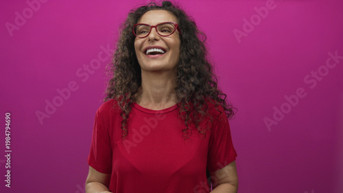 Bilde på lerret Hispanic woman wearing red shirt wipes tears from cheeks in studio; sadness sorrow grief vulnerability