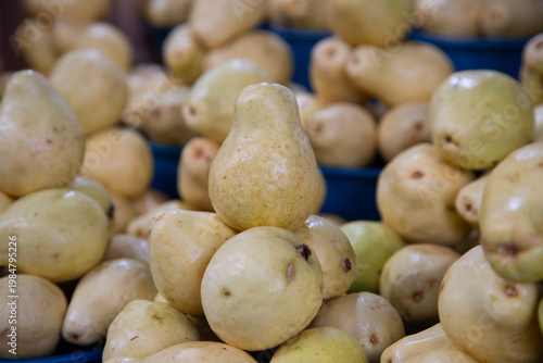 Fresh pears displayed in buckets at a vibrant Mexican market stall in Chiapas, Mexico.