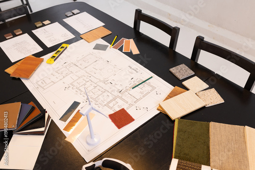 Architectural plan sitting on table in studio with veneer, pencils, spirit level and turbine model