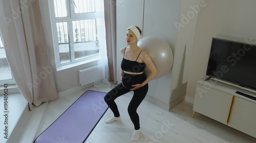 Exercises for pregnant women on fitball. Back massage with fitball. Pregnant woman strengthens her back muscles, doing exercises at home. Preparing for childbirth, relaxing pelvic floor muscles.
