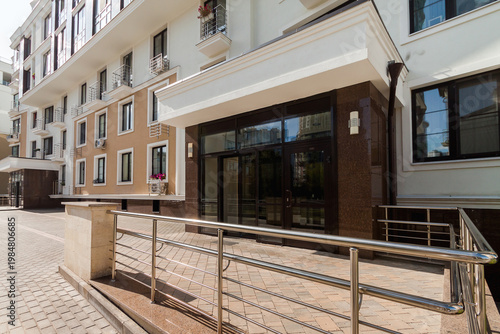 Entrance of modern residential apartment building with glass doors and accessibility ramp