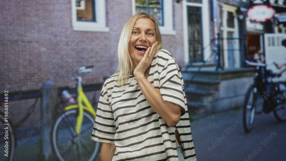 Fototapeta premium Woman with hand covering mouth showing surprised expression on a city street with bicycles and brick building; astonishment candid moment.