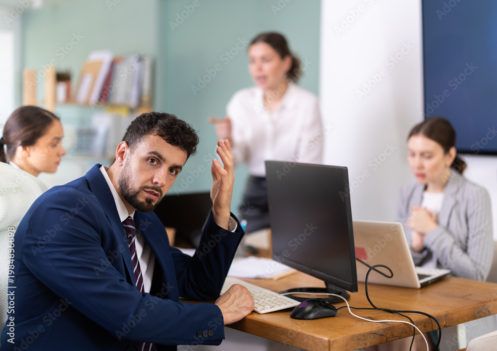 Obraz premium Young woman stands at office desk and scolds group of upset man and women in office