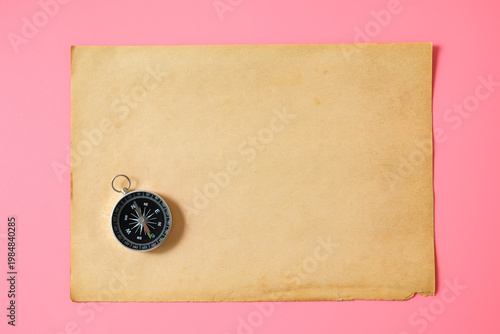 Old paper with vintage compass on color background.