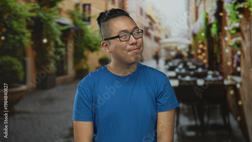 Fotografia Man smiling and looking sideways, wearing glasses at a restaurant terrace on a street; quiet contentment