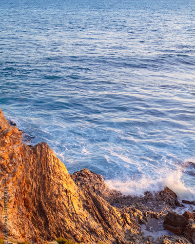 High angle view of waves breaking on rocks on the beach at sunset